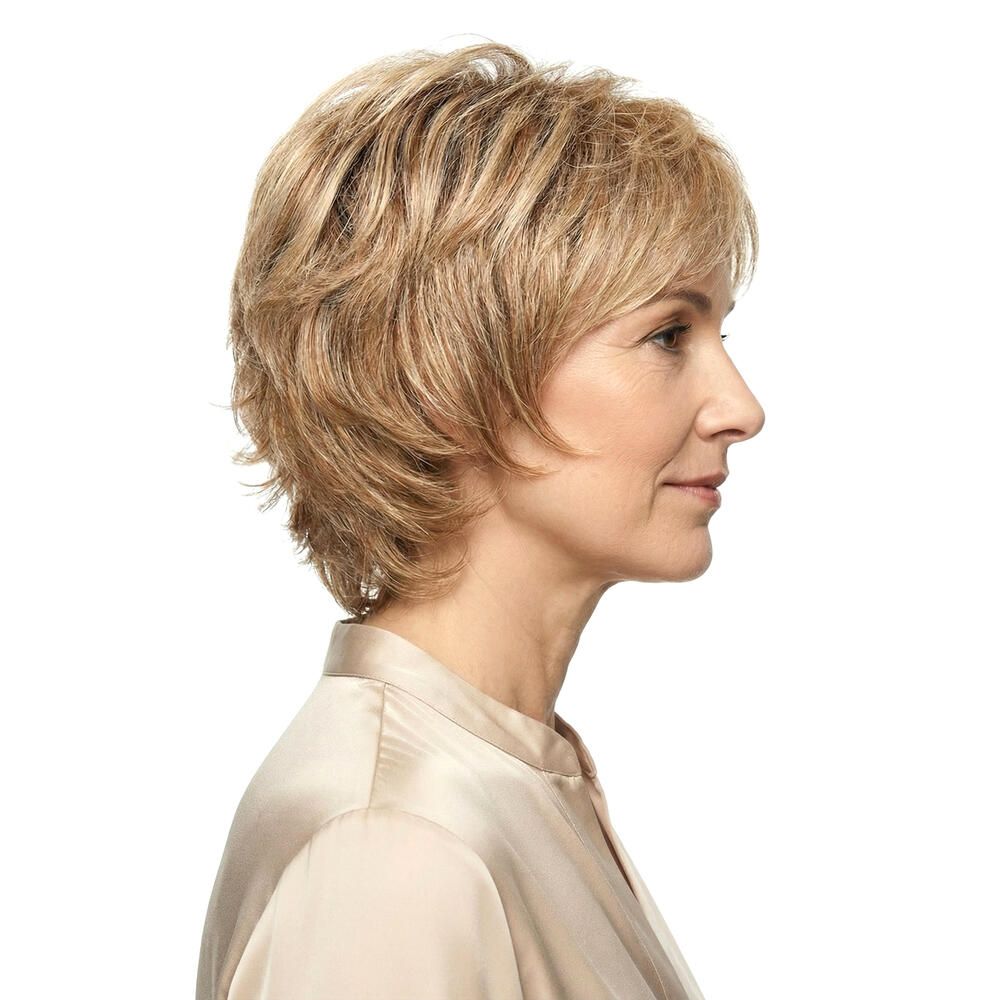 Seitenansicht einer Frau mit einer blonden Kurzhaarperücke. Die Haare sind gestuft und fallen locker. Die Perücke bedeckt den Kopf.