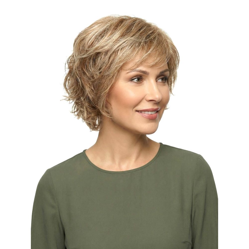 Kurzhaarperücke mit blonden Strähnen. Nahaufnahme einer Frau mit Perücke und grünem Oberteil. Blick in die Kamera.