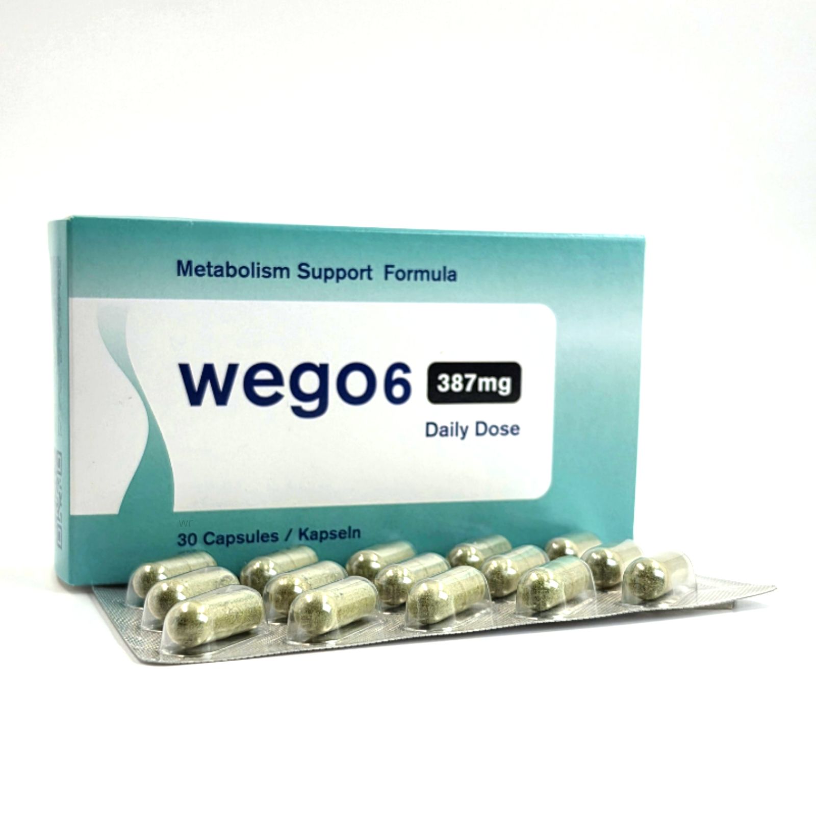 Schachtel und Blisterpackung mit Kapseln. Auf der Schachtel steht "Wego6", "387mg Daily Dose" und "30 Capsules / Kapseln".