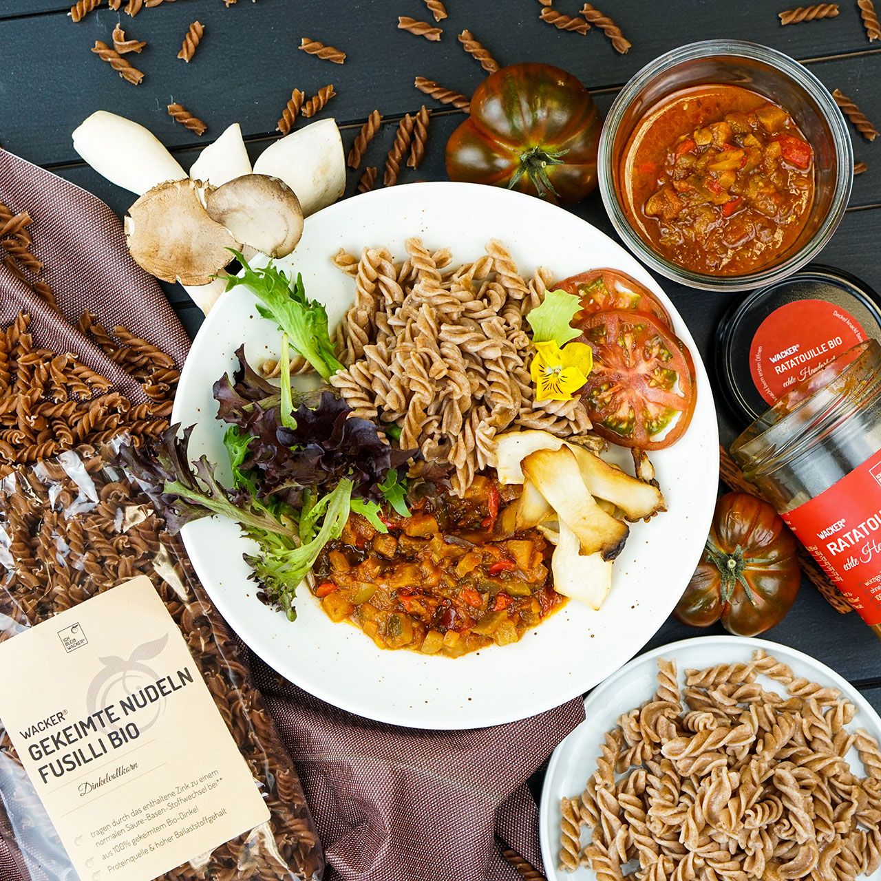 Teller mit Nudeln, Ratatouille, Pilzen und Tomaten. Wacker Ratatouille Bio und Nudeln in Verpackung.