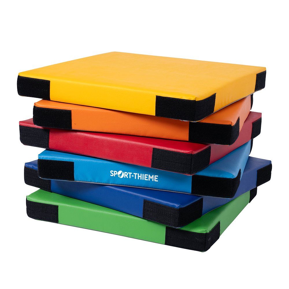 Gestapelte, farbige Turnmatten mit schwarzen Ecken. Das Logo Sport-Thieme ist auf einer Matte sichtbar.