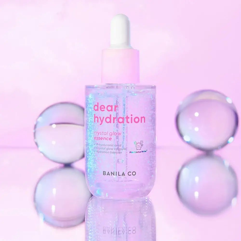 Rosa Serumflasche mit Pipette. Aufschrift: dear hydration, crystal glow essence. Marke: BANILA CO. Hintergrund: Kugeln.