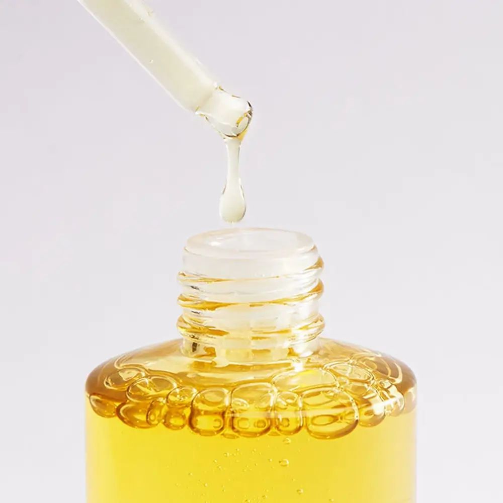 Nahaufnahme einer Serumflasche. Pipette mit Tropfen. Gelbe Flüssigkeit. Klarer Hintergrund.