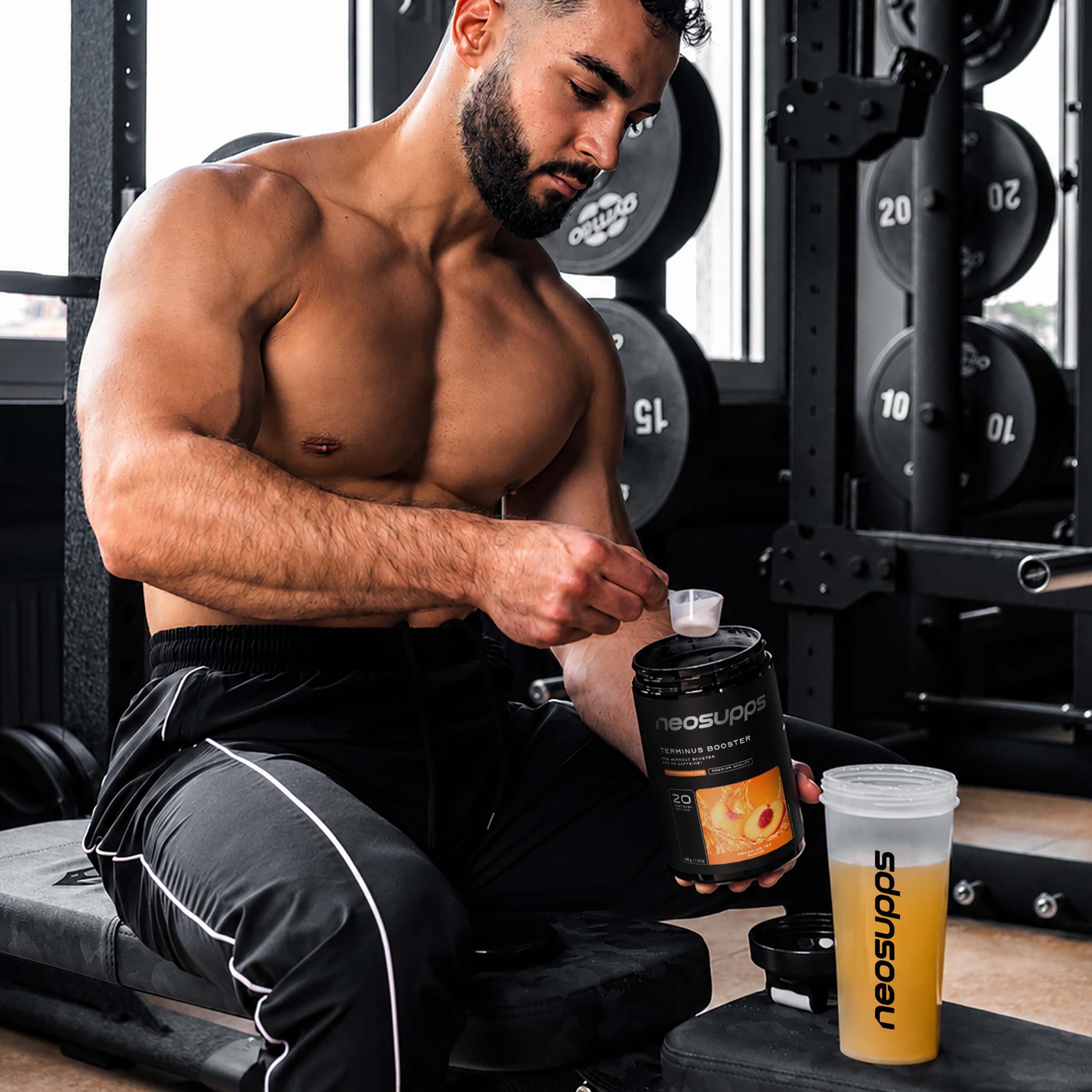 Mann im Fitnessstudio bereitet Getränk zu. Dose und Shaker mit "neosupps" Logo. Produkt: Terminus Booster.