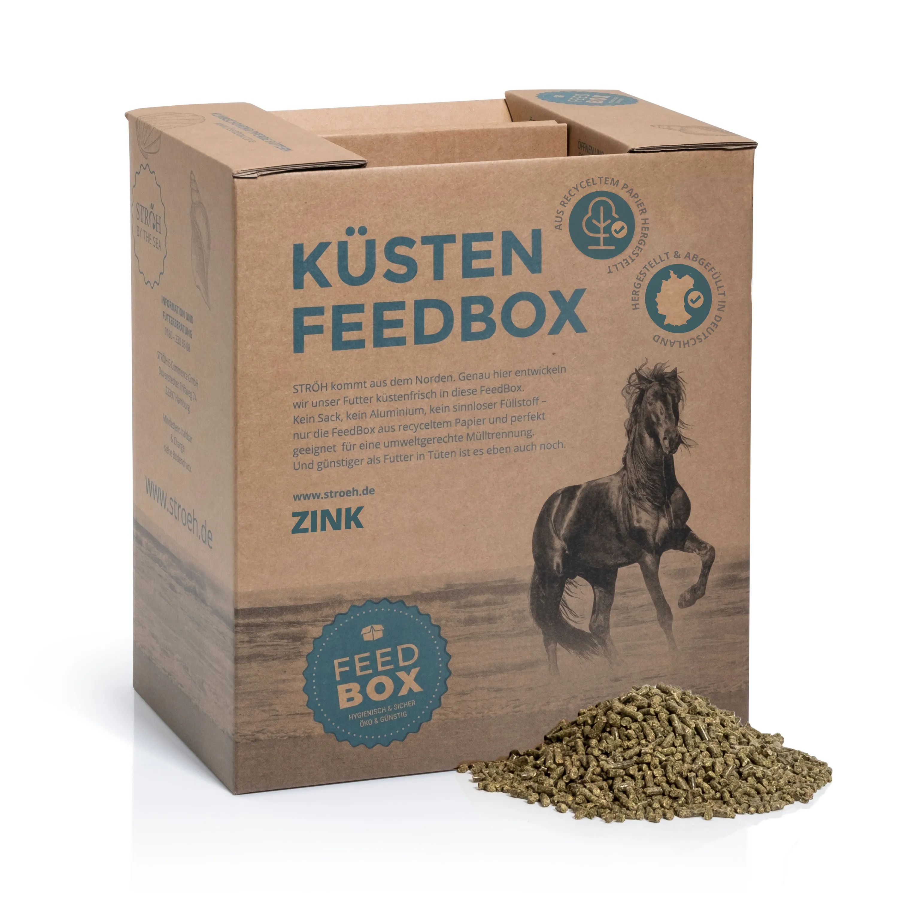Karton "KÜSTEN FEEDBOX ZINK" mit Pferd-Illustration. Grünfutter vor dem Karton. Text: "FEED BOX".
