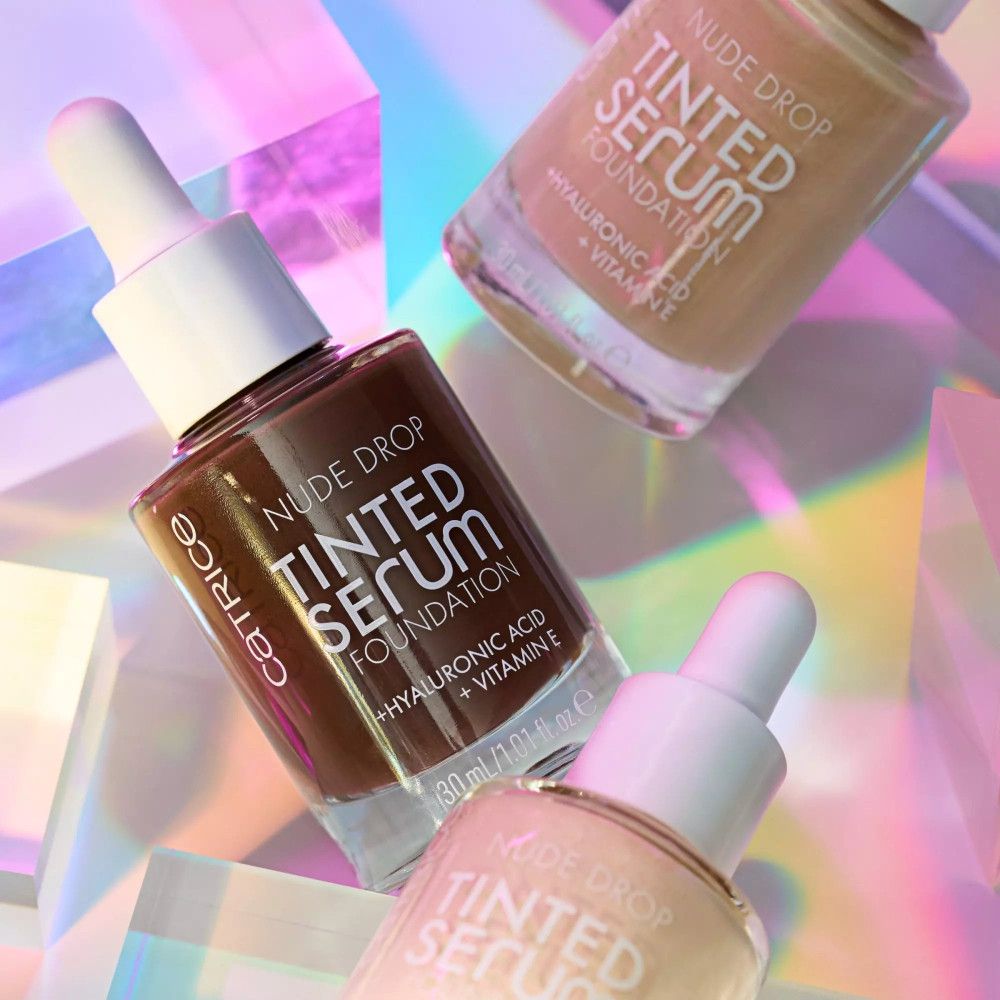 Drei Flaschen Serum. Aufschrift: Nude Drop Tinted Serum Foundation. Verschiedene Farbtöne.