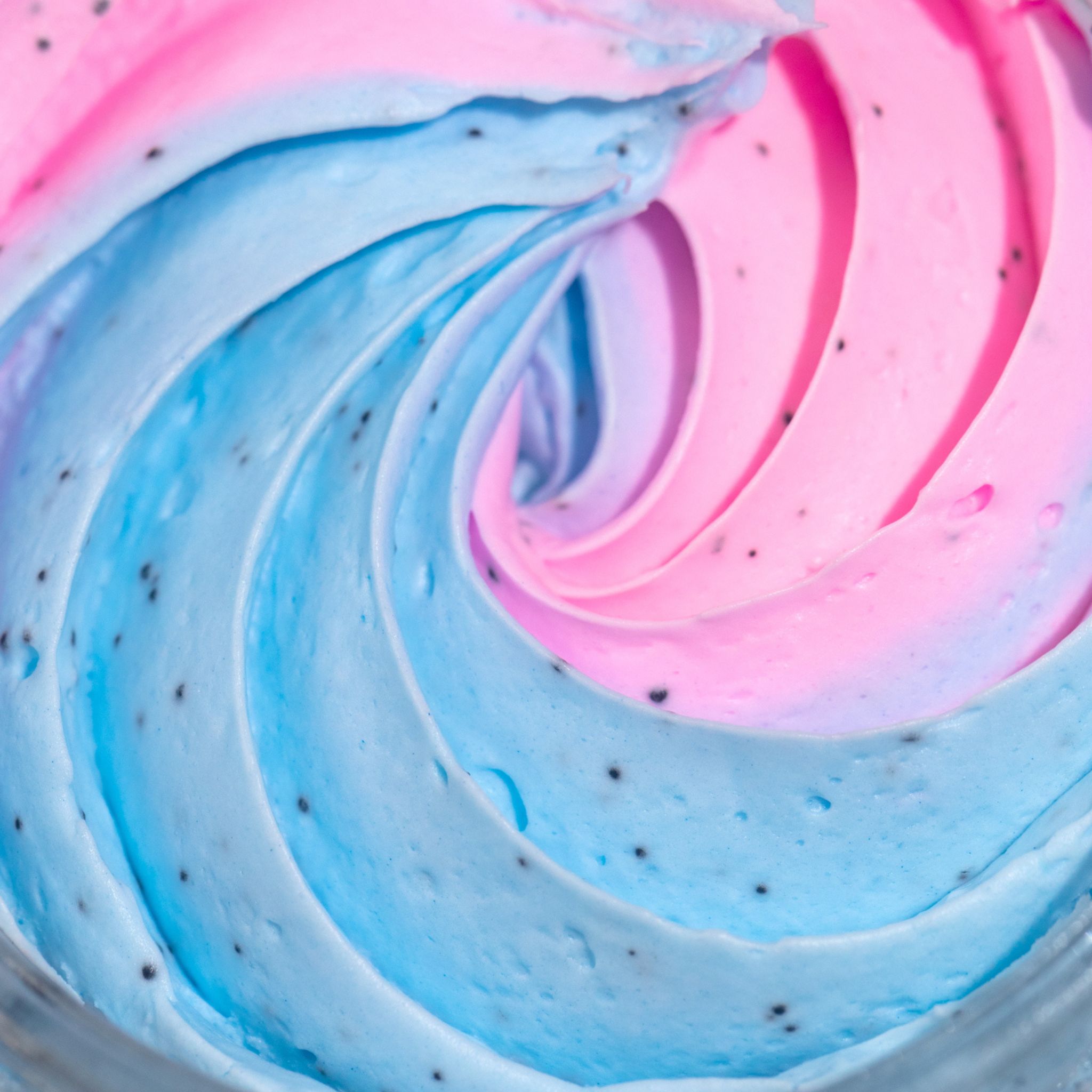 Nahaufnahme von rosa und blau gewirbeltem Produkt mit kleinen schwarzen Punkten.