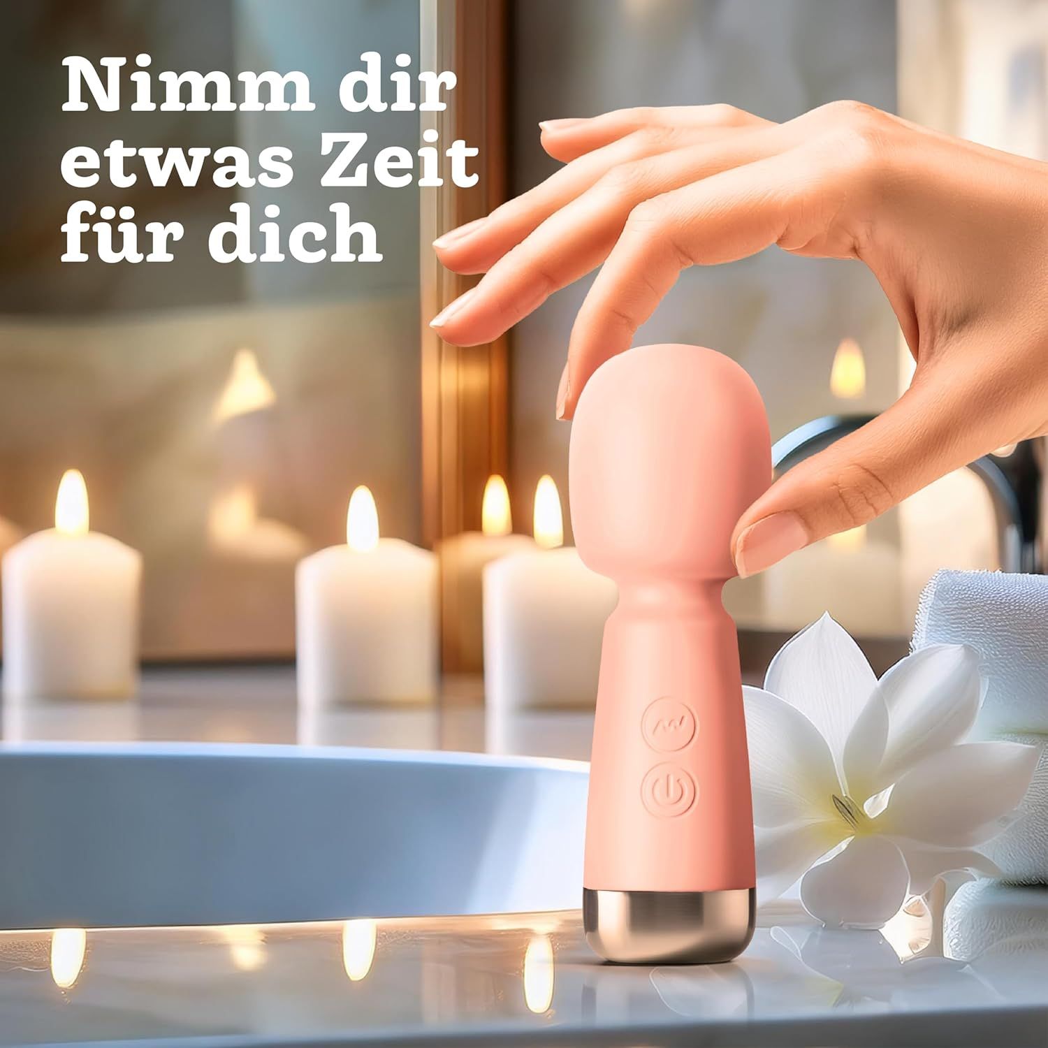 Hand hält einen rosa Mini-Vibrator vor Kerzenlicht und einer Magnolienblüte.