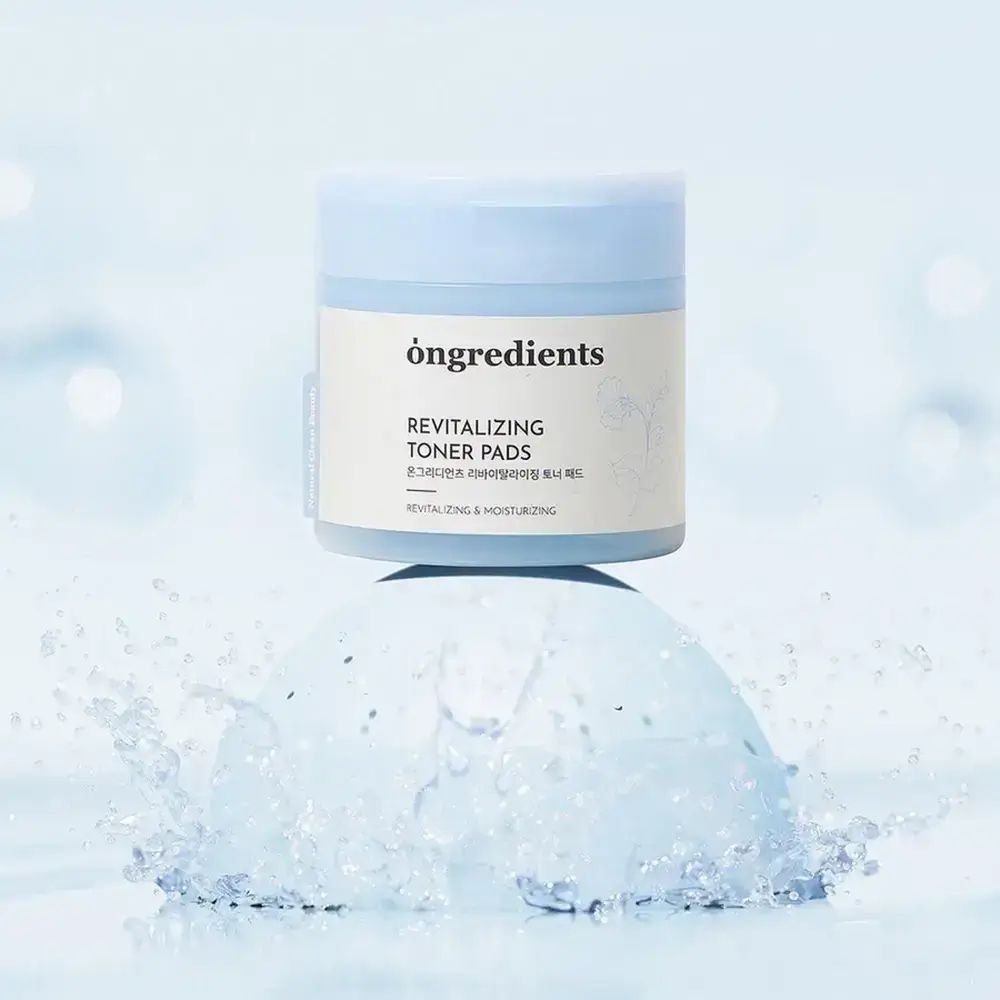 Blau-weiße Dose "ongredients Revitalizing Toner Pads" auf blauem Untergrund. Wasser spritzt um die Dose.