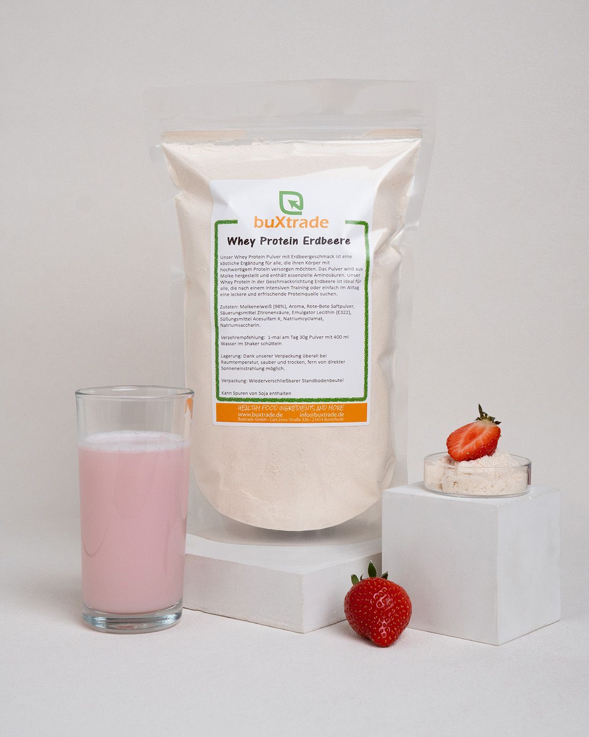 Beutel, Glas mit rosa Flüssigkeit, Erdbeere, halbe Erdbeere. Produktetikett: buXtrade Whey Protein Erdbeere.