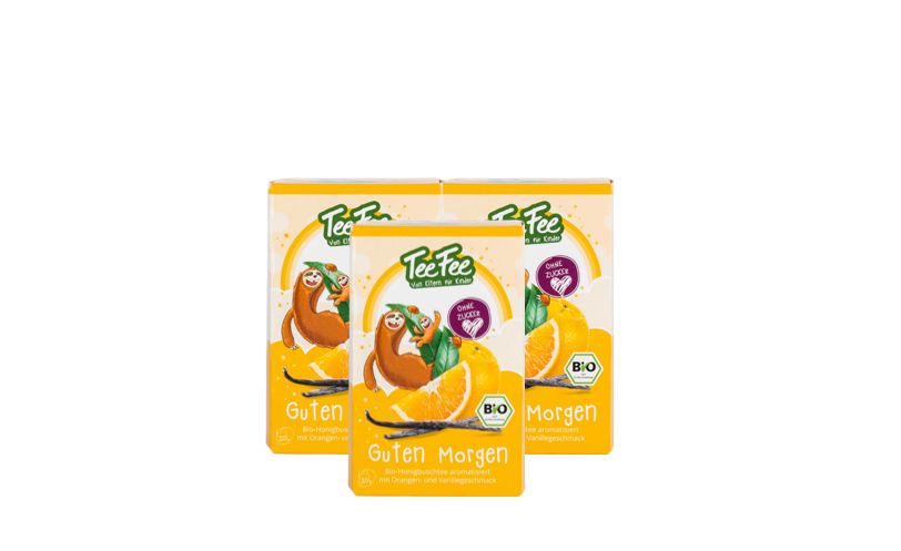 Drei TeeFee-Verpackungen. Aufdruck: Guten Morgen Bio Kräutertee Honeybusch Orange Kindertee. Mit Bio-Siegel.