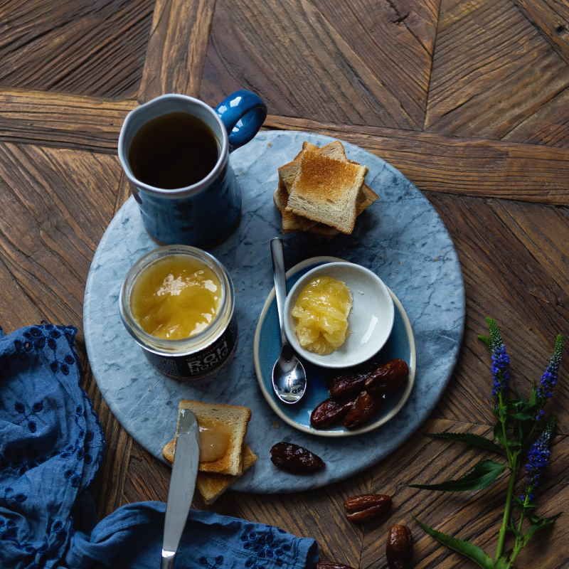 Honig ROH im Glas, serviert mit Toast, Datteln, Tee und Honig in einer Schale auf einem Tablett.