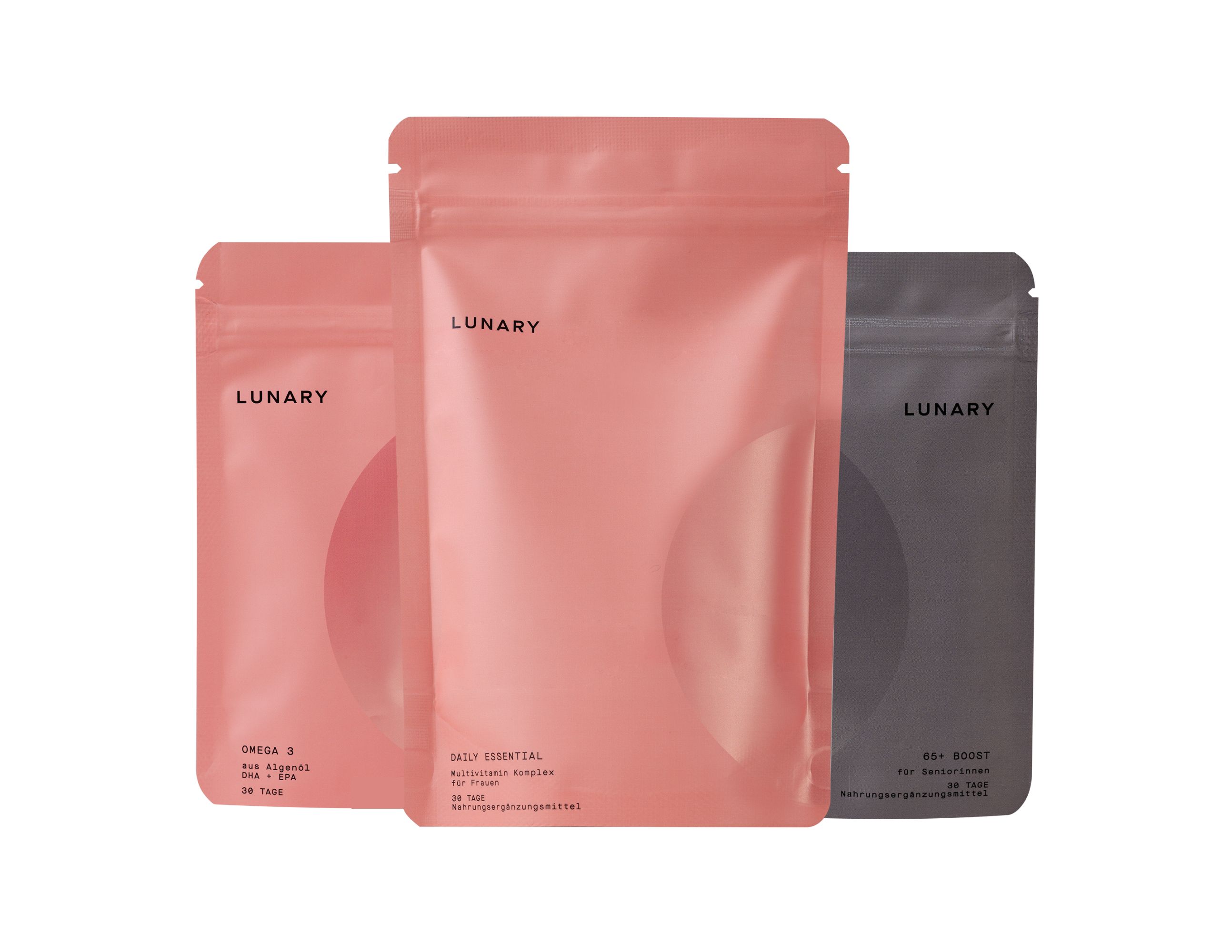 Drei Beutel LUNARY. Rosa, hellrosa und grau. Aufschrift LUNARY. Aufschrift Omega 3, Daily Essential, und Daily Boost.