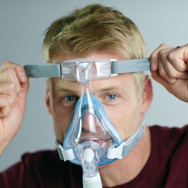 Mann setzt Philips CPAP Maske Amara SE Gel Full Mund-Nasenmaske auf.