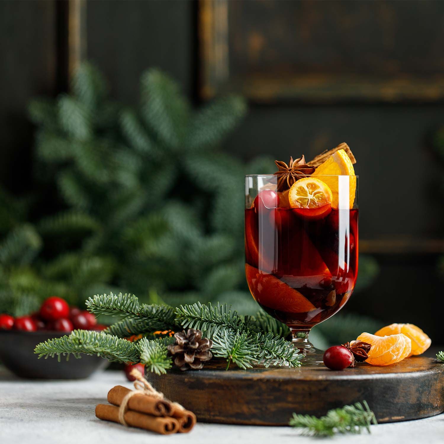 Glas Glühwein mit Gewürzen und Früchten. Zimtstangen, Sternanis, Orangenscheibe. Dekoration mit Tannenzweigen und Cranberries.