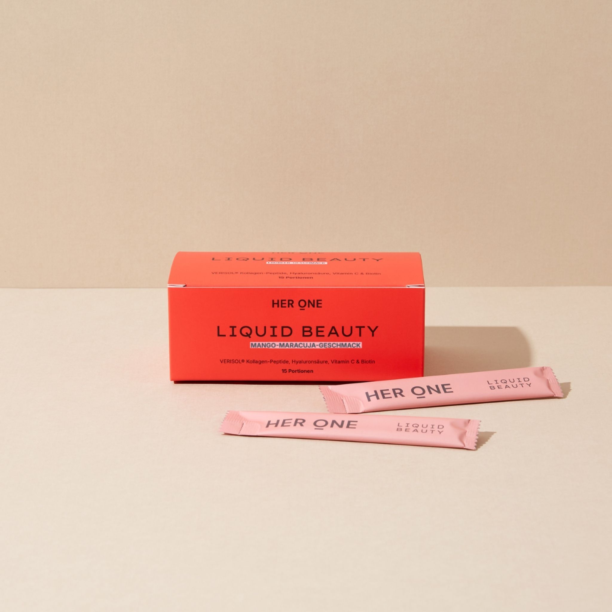 Rote Produktverpackung und drei Einzelsticks mit HER ONE LIQUID BEAUTY Aufdruck. Hintergrund hell.