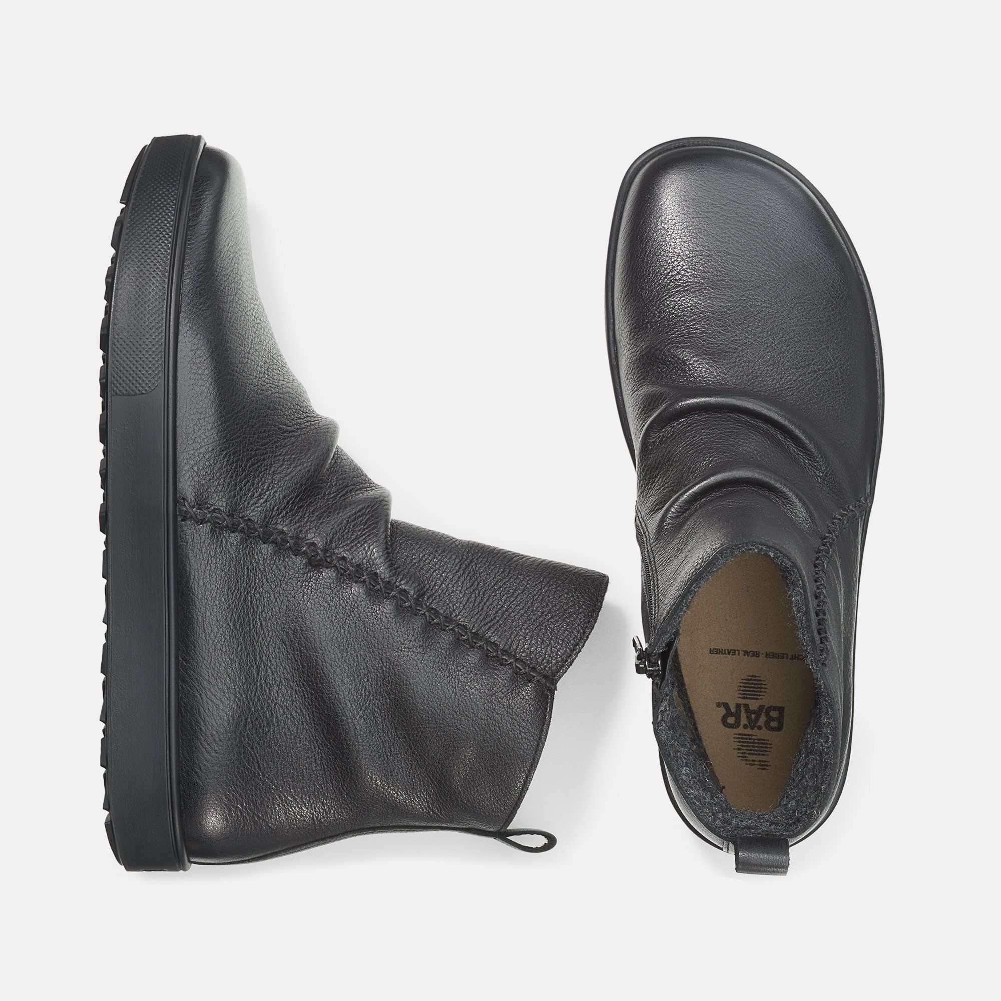 Schwarze Stiefeletten, Draufsicht. Ein Schuh mit Reißverschluss, der andere mit Innenfutter und Logo.