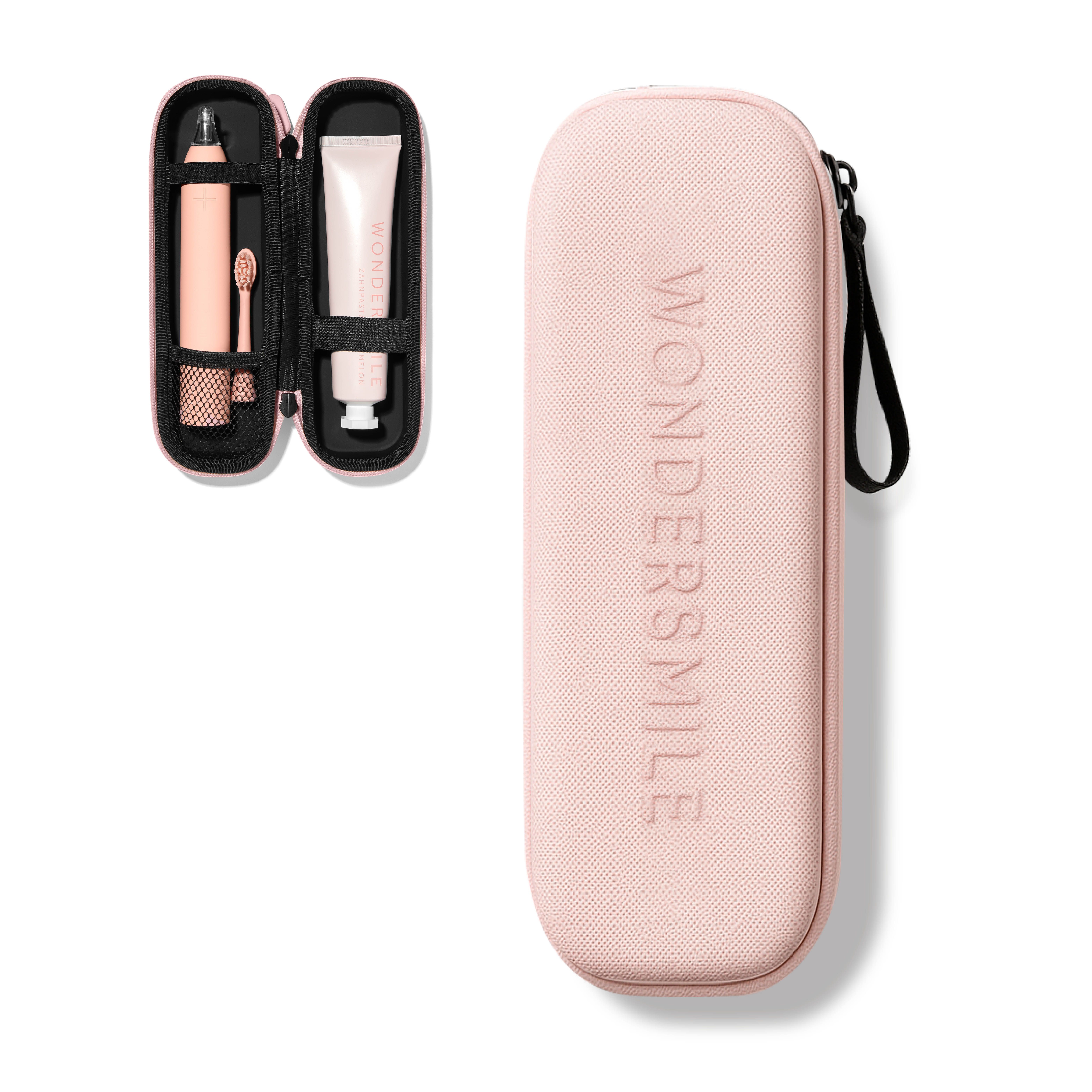 Rosa Reiseetui, geöffnet mit Zahnbürste, Zahnpasta und Halterung. Geprägter Schriftzug: Wondersmile.