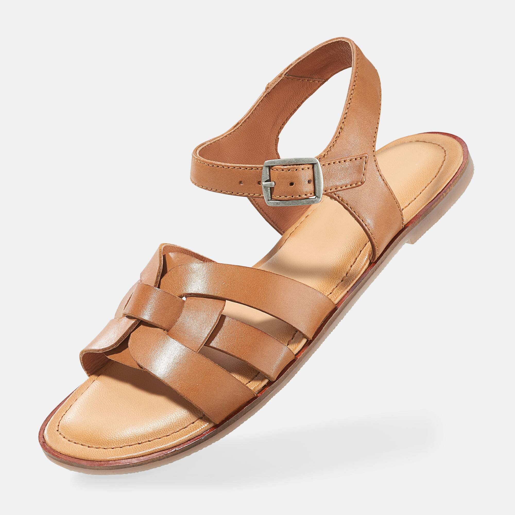 Braune Sandale mit geflochtenem Riemen und Schnalle. Flache Sohle. Perspektivische Ansicht.