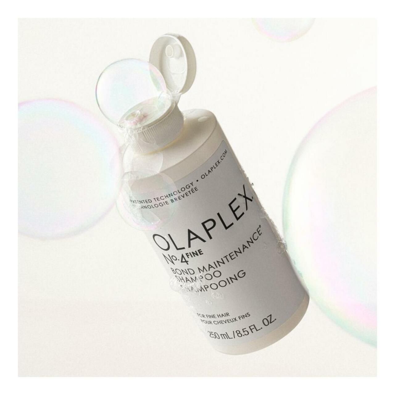 Olaplex No.4 Fine Bond Maintenance Shampoo Flasche, weiß, mit geöffnetem Deckel. Blasen im Hintergrund.