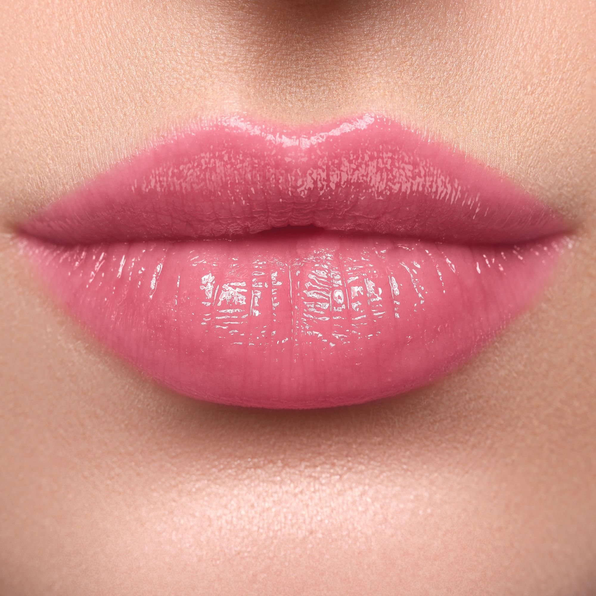 Nahaufnahme von Lippen mit glänzendem, rosafarbenem Lippenstift.