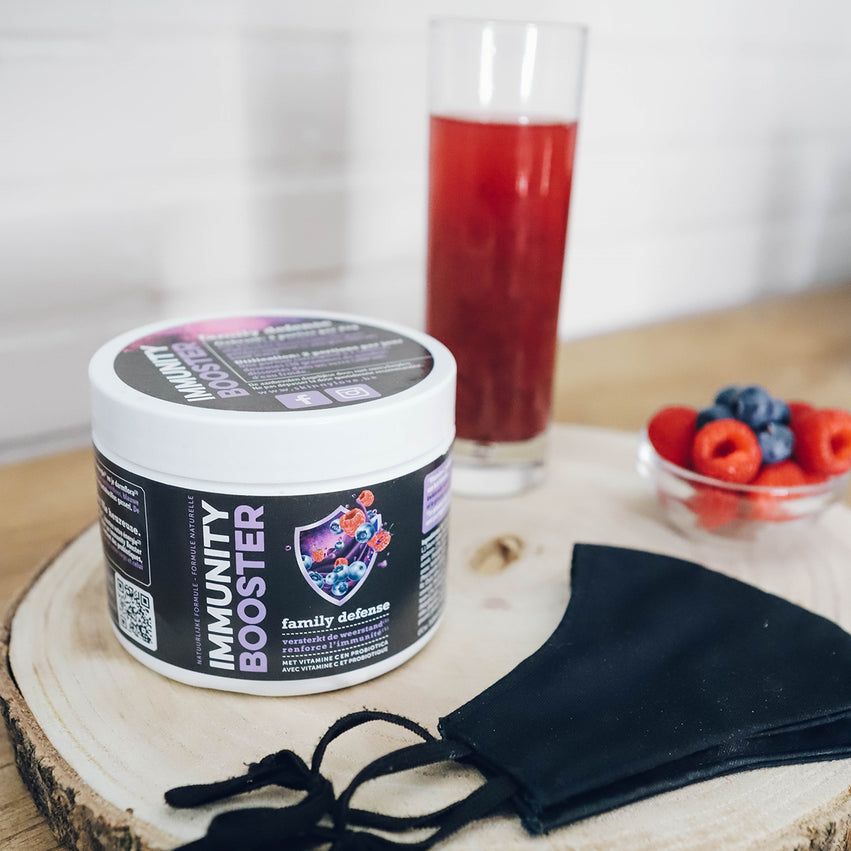 Behälter mit Produktetikett. Glas mit rotem Getränk. Schale mit Beeren. Schwarze Maske auf Holzbrett.