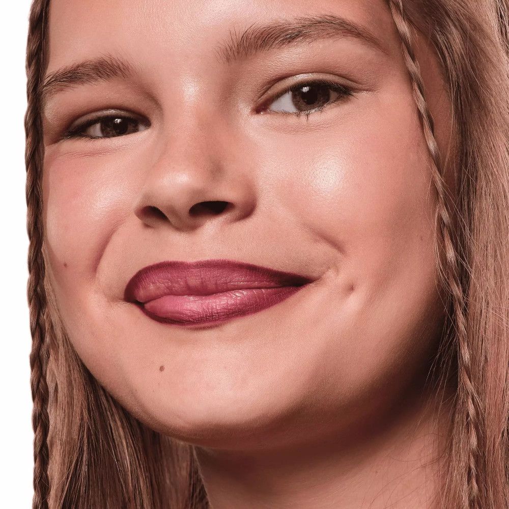 Nahaufnahme eines lächelnden Mädchens mit geflochtenen Haaren und rosafarbenen Lippen.