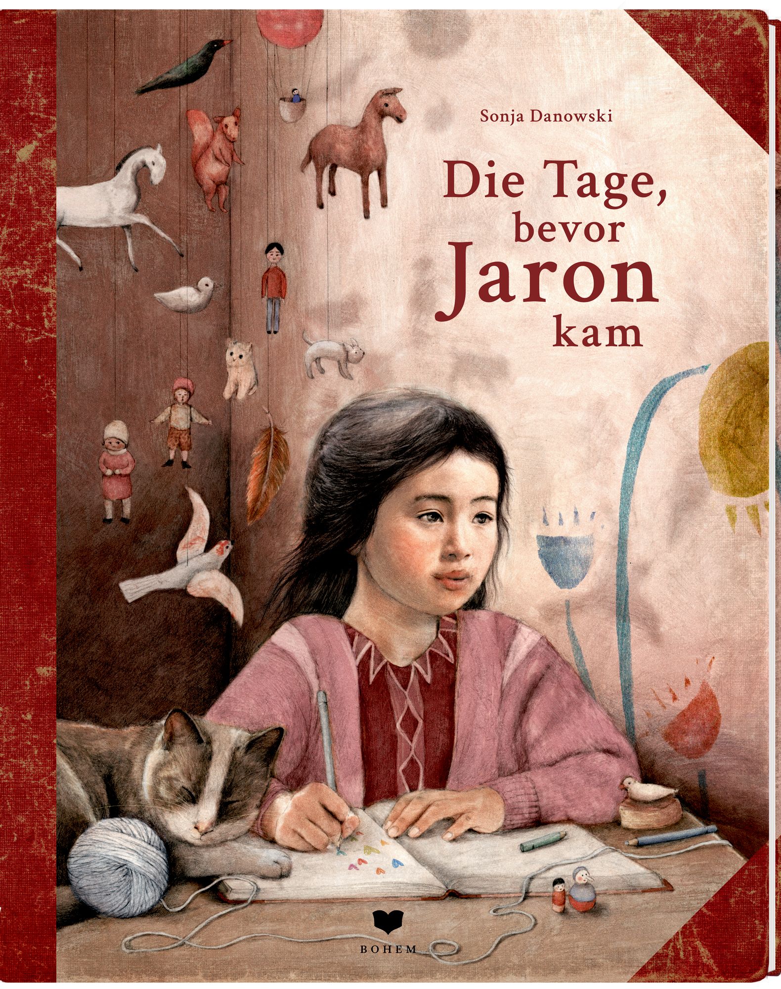 Buchcover: Titel "Die Tage, bevor Jaron kam" von Sonja Danowski. Illustration einer jungen Frau, die schreibt, mit Katze und Spielzeug.