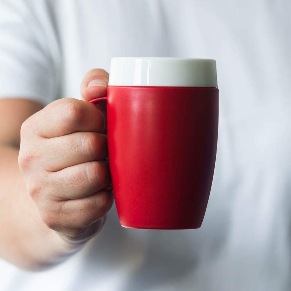 Roter Becher mit weißem Trinkaufsatz. Eine Hand hält den Becher. Kleiner Henkel.