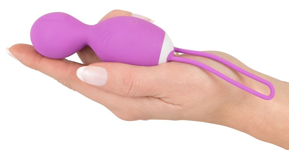Hand hält lila Vibrokugel-Duo. Duo mit zwei Kugeln, verbunden mit einem Band. Auf der Handfläche liegend.