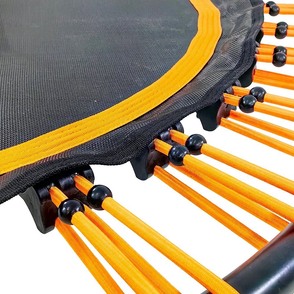 Nahaufnahme Trampolin-Details. Schwarze Sprungfläche, orangefarbene Gummibänder. Schwarze Kugeln.