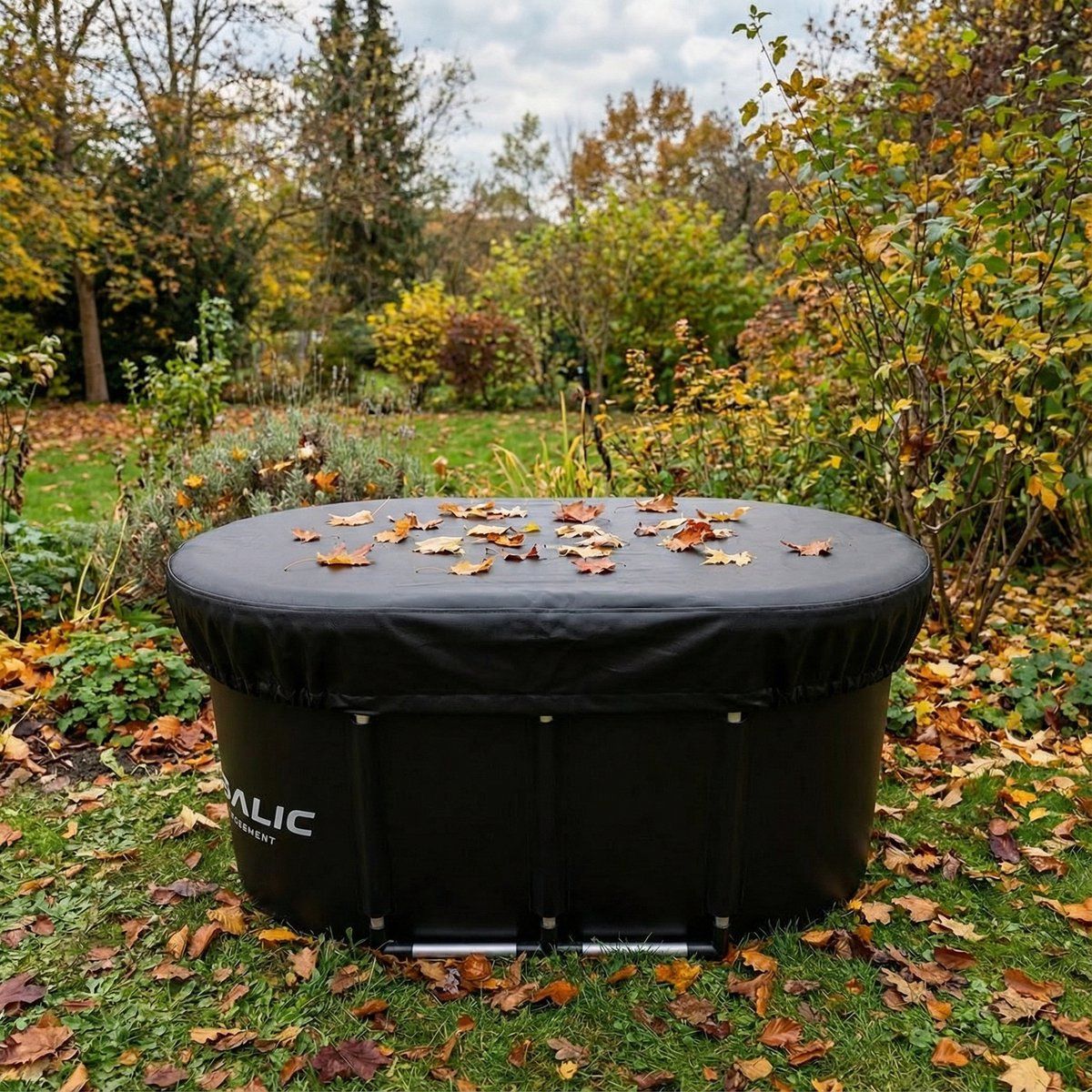 Schwarzes Eisbad mit Deckel, bedeckt mit Blättern. Steht auf Rasen. Herbstliche Umgebung.