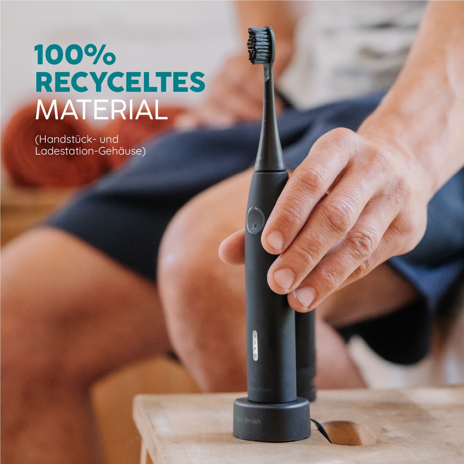 Schwarze Schallzahnbürste in einer Hand. Text: '100% recyceltes Material'.