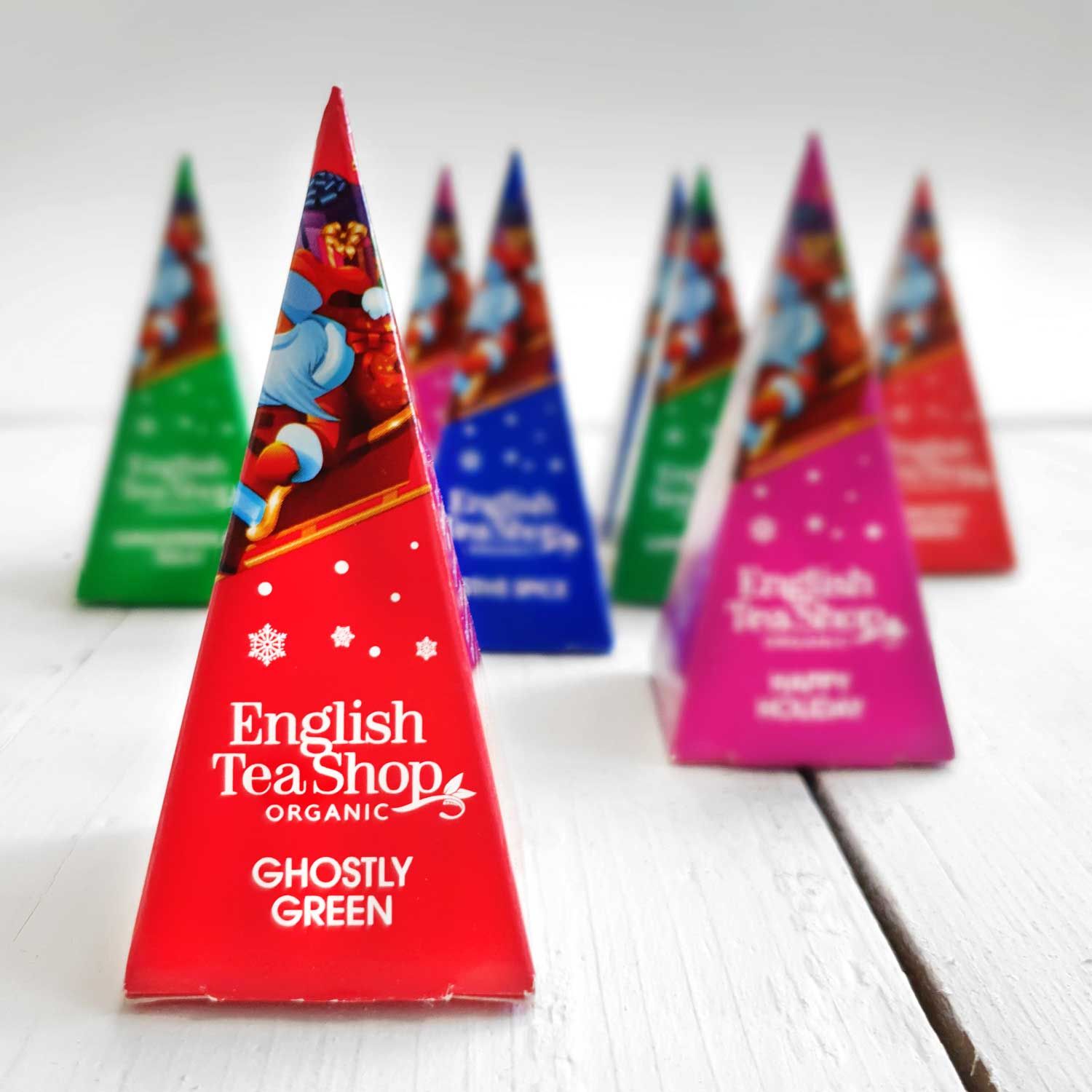 Mehrere pyramidenförmige Teebeutel. Aufdruck: English Tea Shop, verschiedene Farben. Aufschrift: Ghostly Green, Happy Holiday.