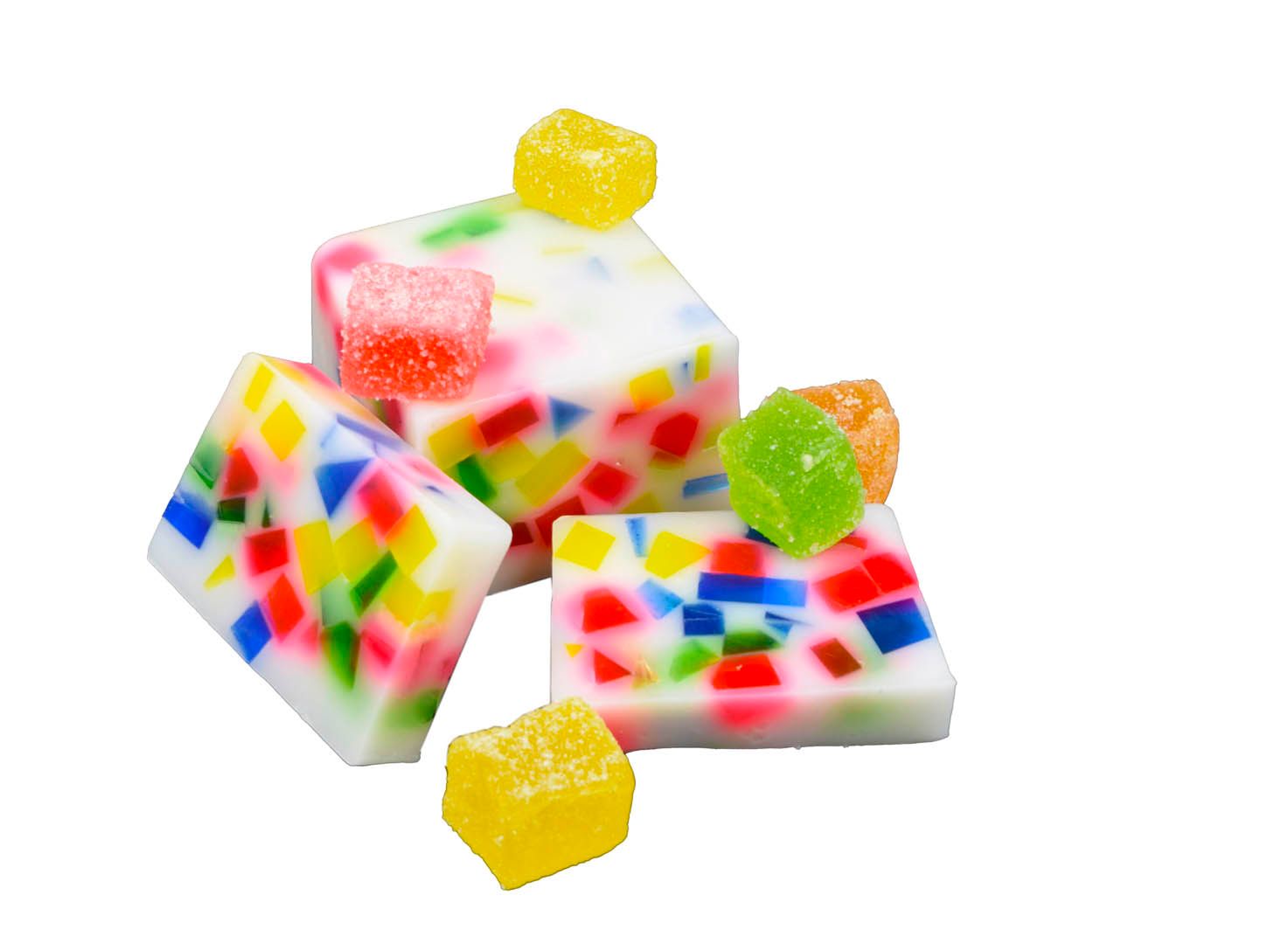 Mehrere weiße Seifenstücke mit bunten, mosaikartigen Einlagen und farbigen Geleestücken. Einige Stücke sind quadratisch, andere rechteckig.