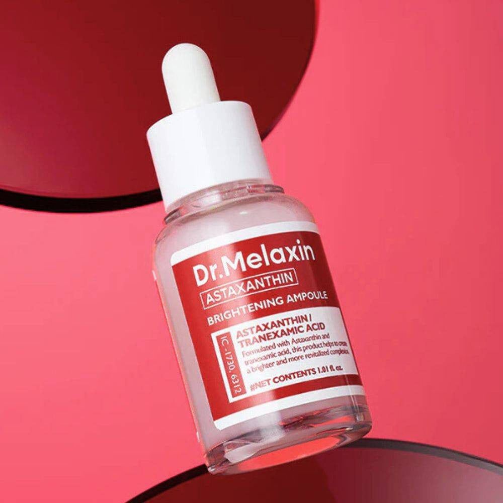 Klare Glasflasche mit weißem Deckel und rotem Etikett. Text: Dr. Melaxin, Astaxanthin, Brightening Ampoule. Tropfer.