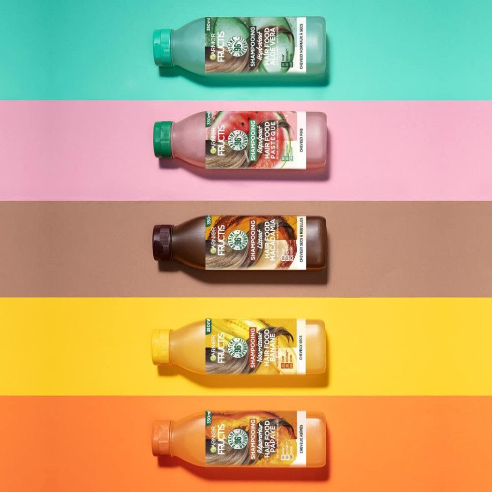 Fünf Flaschen Garnier Fructis Hair Food Shampoo, verschiedene Farben, auf farbigen Hintergründen. Etiketten mit Produktnamen.