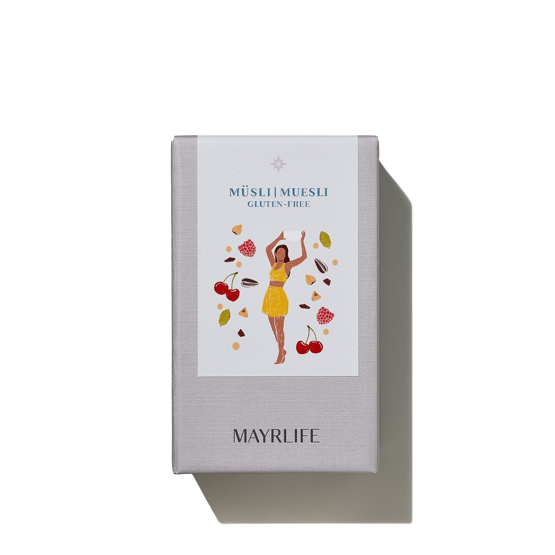 Graue rechteckige Verpackung mit Aufdruck. Auf dem Etikett: Müsli, glutenfrei, Illustration einer Frau, Kirschen, Nüsse. MAYRLIFE.