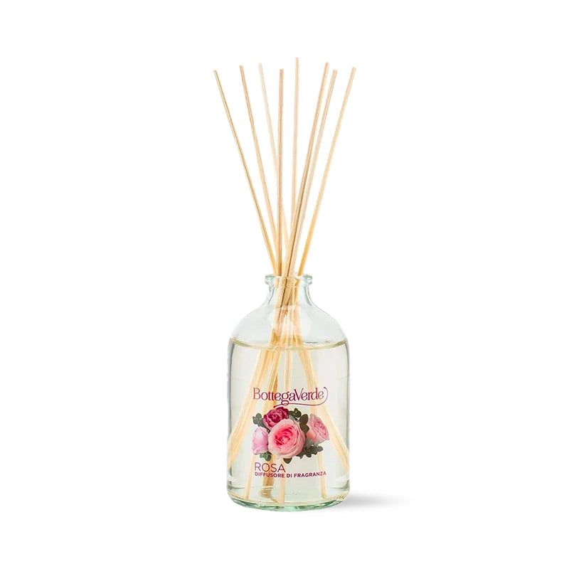 Diffusore di fragranza Bottega Verde Rosa. Bottiglia di vetro trasparente con liquido e bastoncini di legno. L'etichetta mostra il marchio, rose e la scritta "Rosa Diffusore di Fragranza".