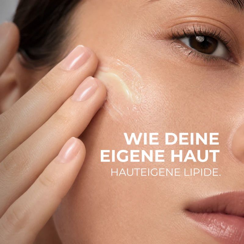 Eine Hand trägt eine Creme auf die Wange einer Frau auf.