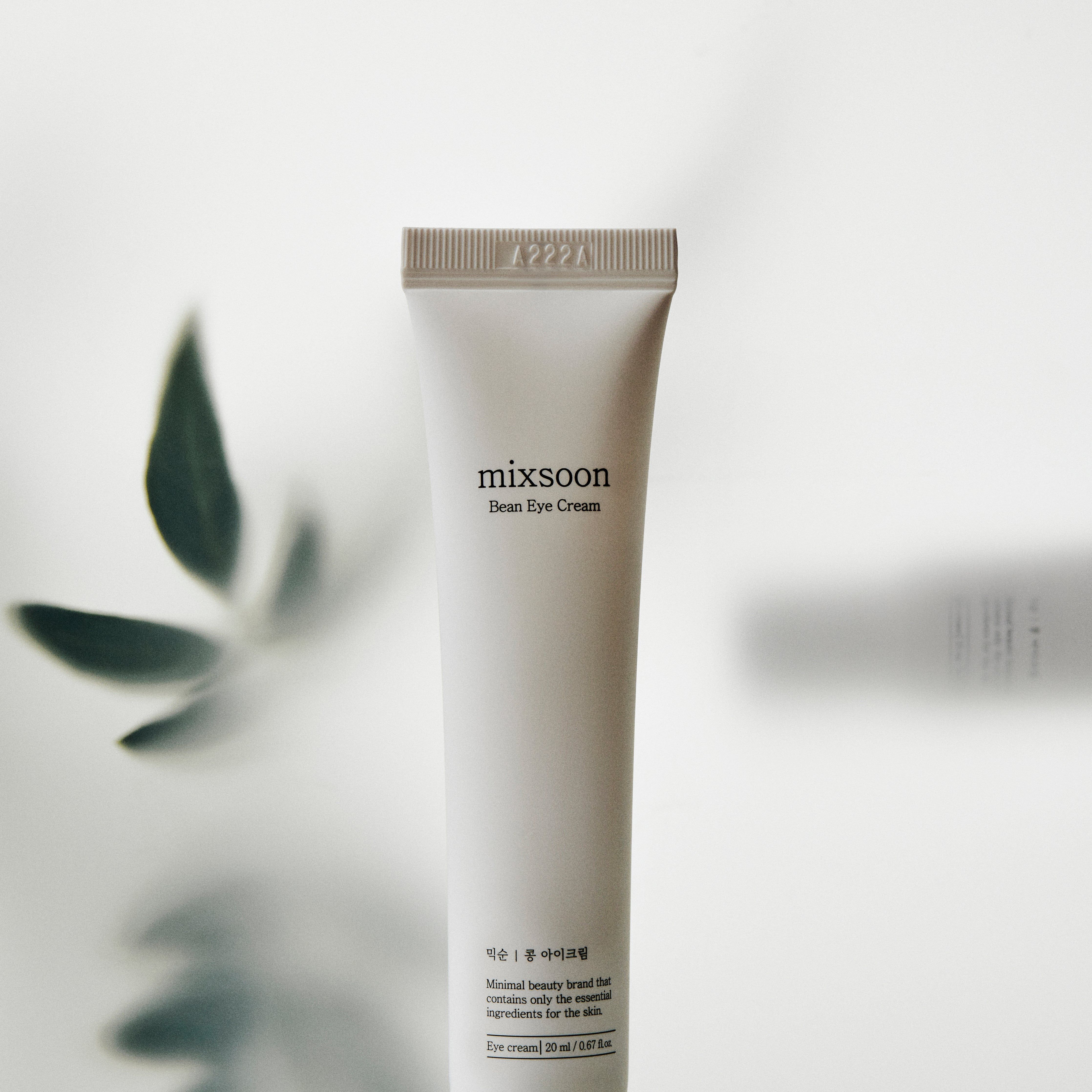 Weiße Tube "mixsoon Bean Eye Cream" mit Text. Blätter im Hintergrund. 20 ml.