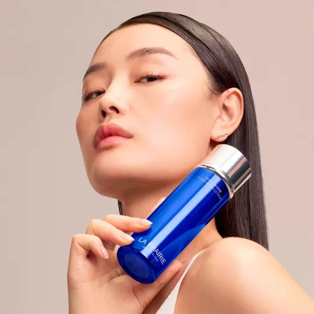 Frau hält La Prairie Skin Caviar Essence-in-Lotion Flasche.