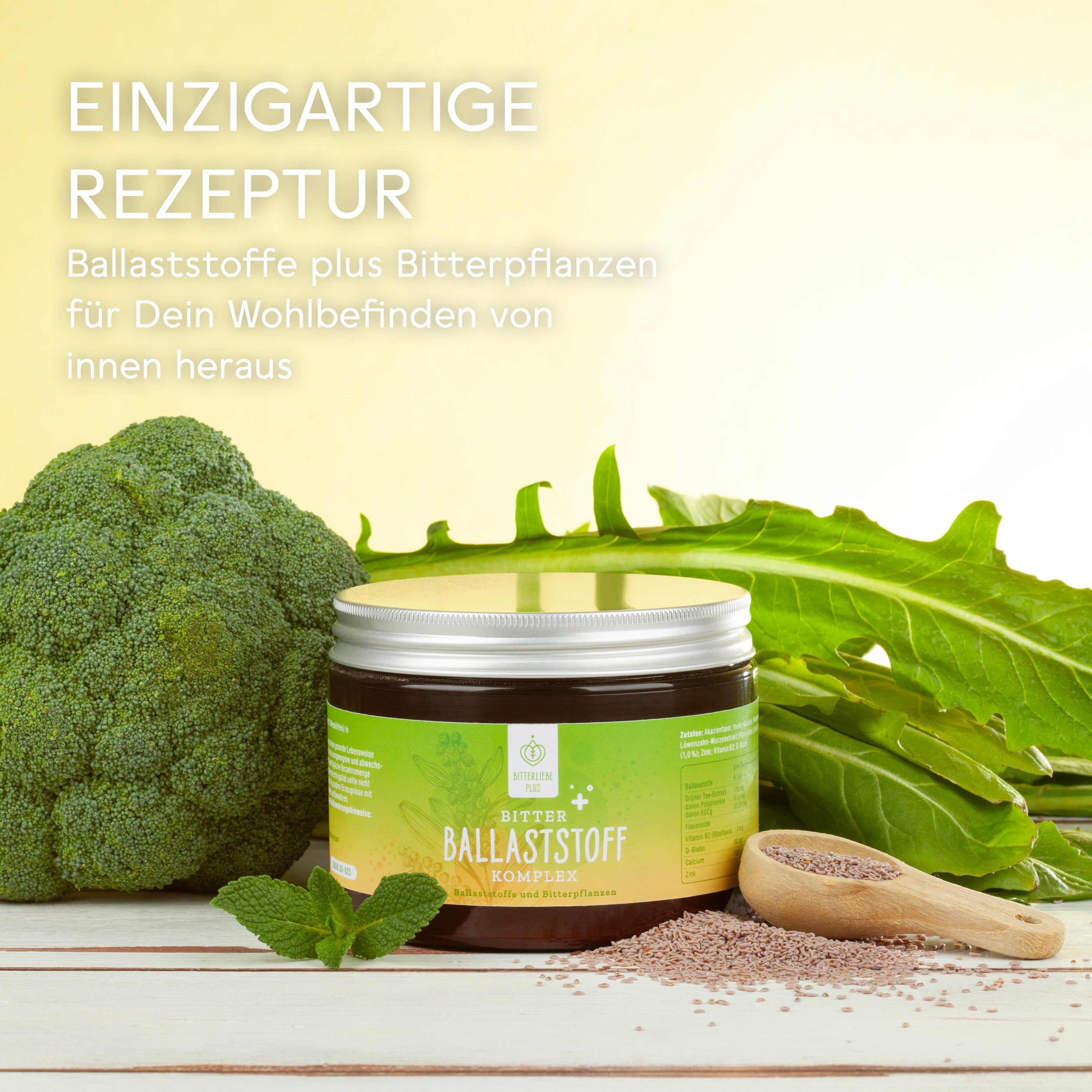 Dose mit gelb-grünem Etikett, Text: BitterLiebe Ballaststoff Komplex. Umgeben von Gemüse und Leinsamen. Holz-Löffel.