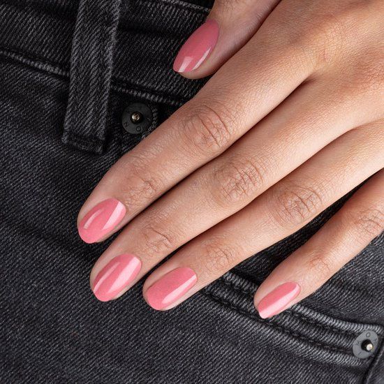 Hand mit lackierten Nägeln in Rosa. Die Hand liegt auf einer Jeans.
