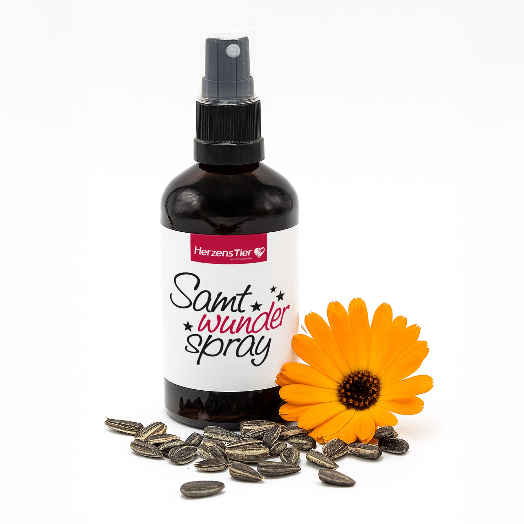 Braune Sprühflasche mit weißem Etikett und Aufschrift. Daneben Sonnenblumenkerne und eine Blüte.