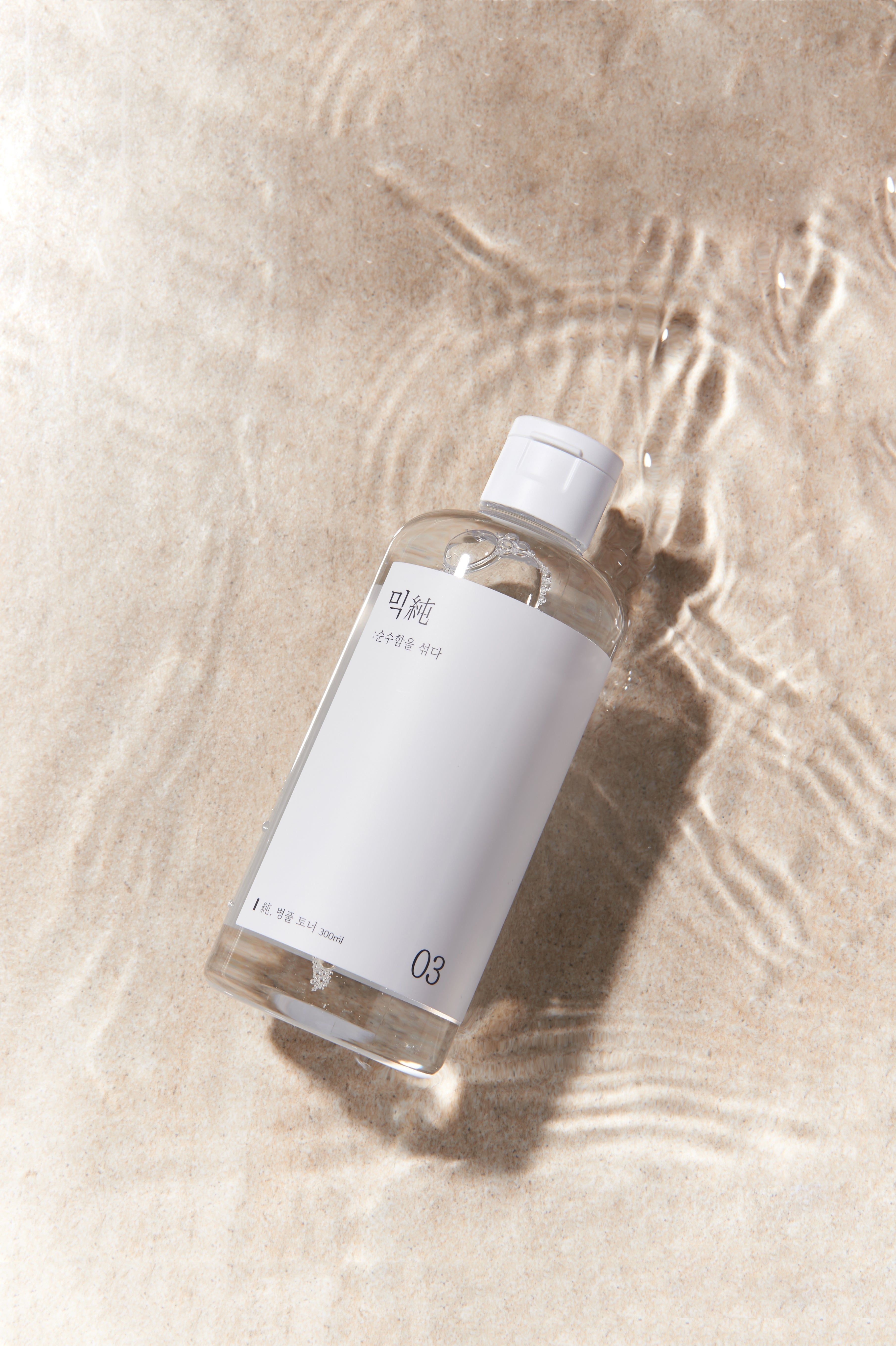 Transparente Flasche mit weißem Deckel und Etikett, im Wasser. Aufschrift in koreanischer Schrift und die Zahl 03. Aufschrift: 200ml.