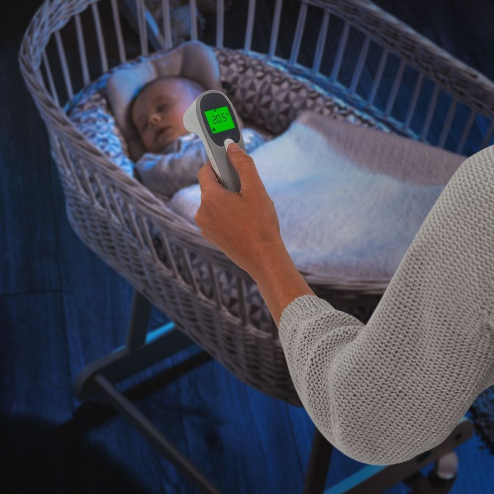 Infrarot-Thermometer misst die Temperatur eines schlafenden Babys. Das Thermometer zeigt 36,5°C an. Marke: reer.