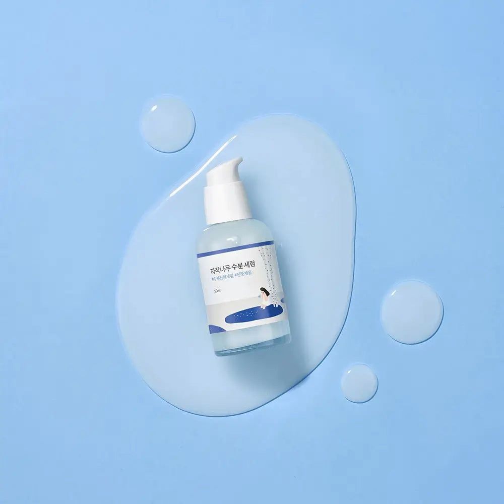 Klare Flasche mit weißem Pumpkopf. Aufkleber mit Schriftzeichen und Illustration. Liegt auf einer blauen Flüssigkeit.