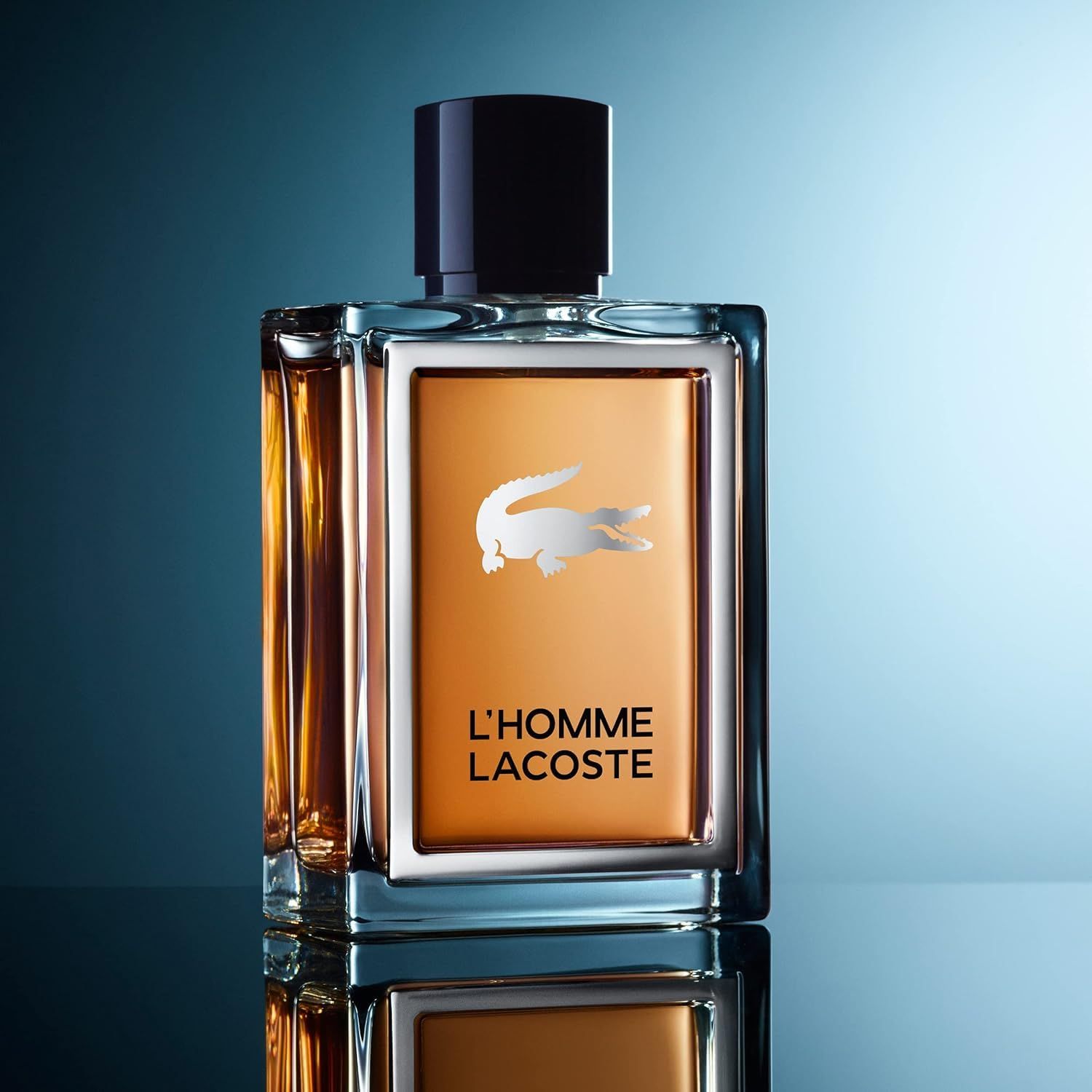 Lacoste L'Homme Eau de Toilette Flakon auf reflektierender Oberfläche vor blauem Hintergrund.