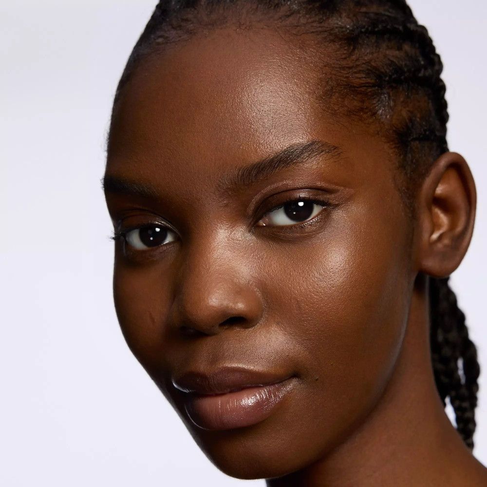 Nahaufnahme einer Frau mit dunkler Haut und geflochtenen Haaren. Sie trägt Make-up.